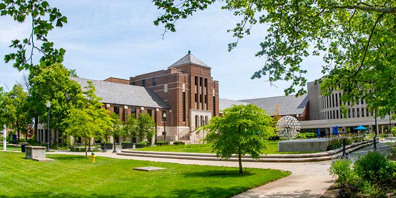 An image of Tirey Hall from across the quad during summer. Parsons Hall and the Trumpets artwork are also visible in the distance.