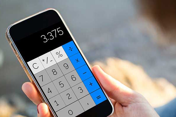 A person’s hand holds a calculator with a digital display. The display’s buttons are blue down the right side, white across the top, and a grey block between them. The readout shows a number: 3.375.