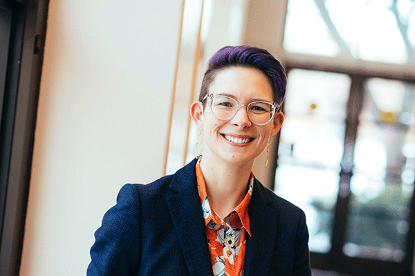 White female faculty member with glasses smiling at the camera