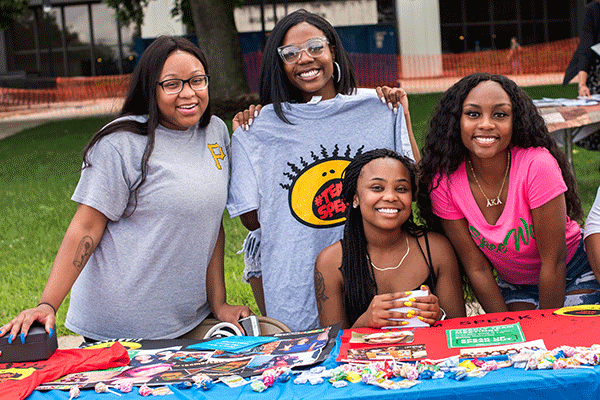 A group of African American students pose for a photo while sitting at a table during the annual Street Fair at the Charle Brown African American Cultural Center.