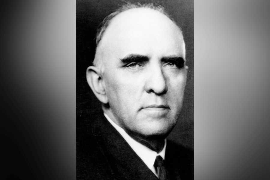  A black-and-white photograph of a man (President Linnaeus Neal Hines) with short hair. He looks straight ahead. He wears a suit, a white shirt, and a tie. A grey border is around the photograph.&nbsp;