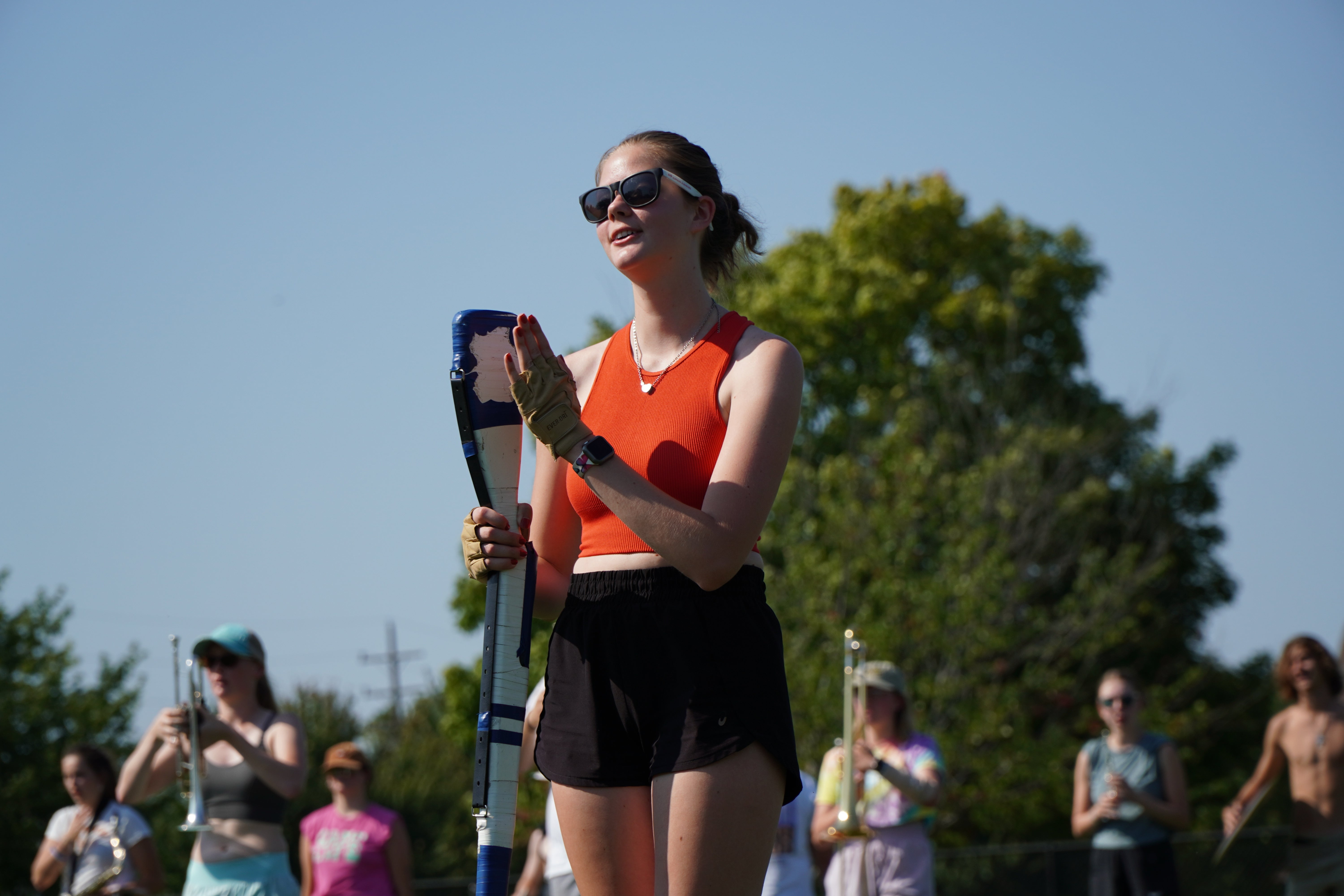 A girl wearing a red top is marching.