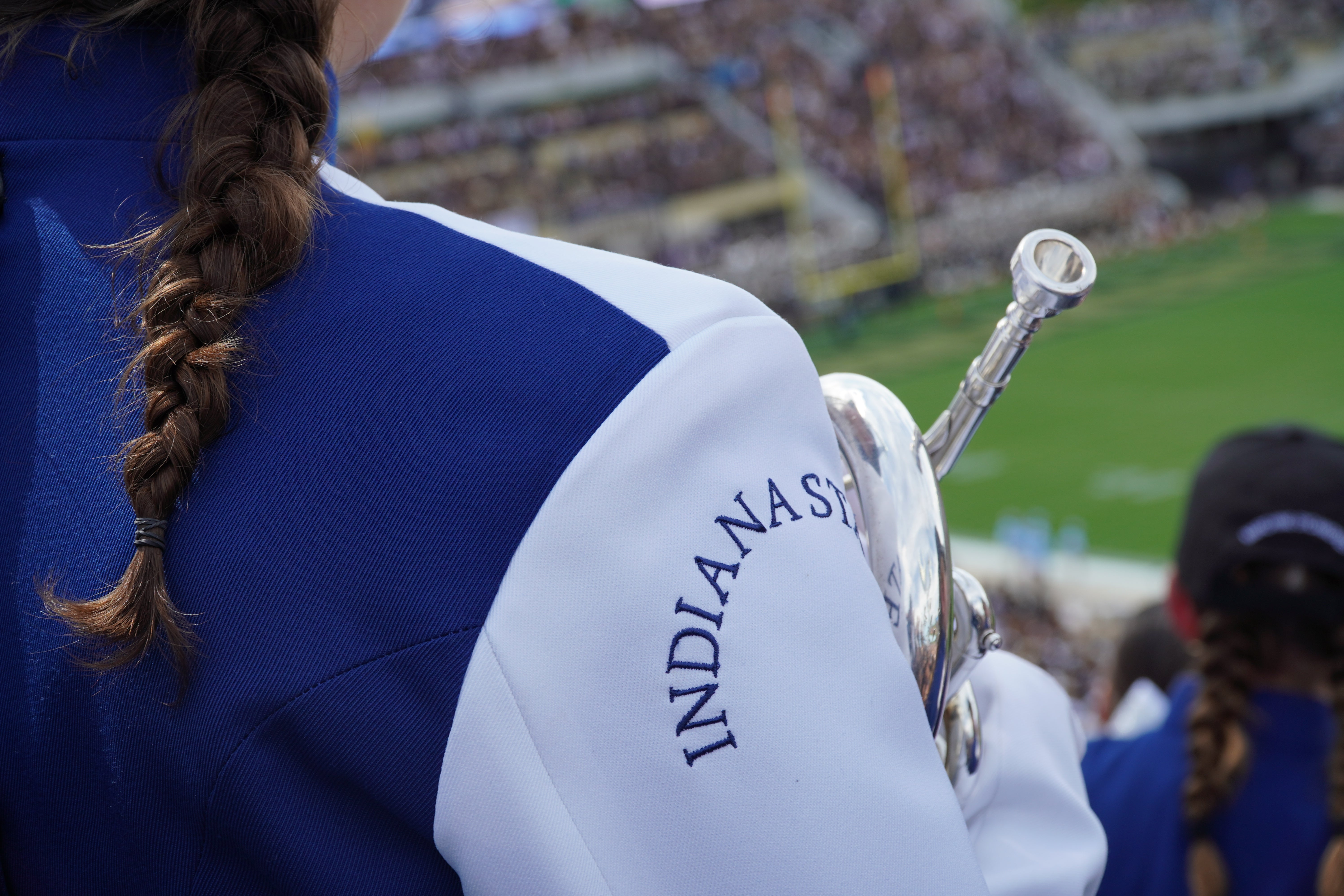 A photo looking over the shoulder of one of the band members at a football game.
