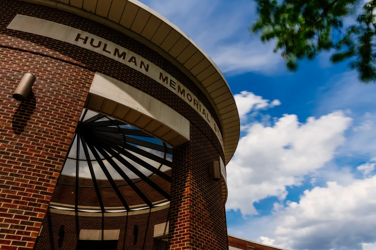 Exterior view of Hulman Memorial Student Union brick building under a blue sky with clouds.