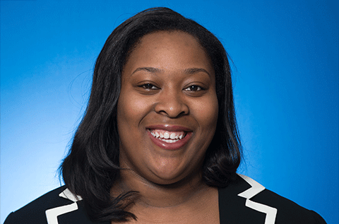 Portrait of a smiling woman against a blue background.”